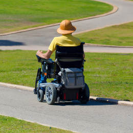 Man in wheelchair strolling down an inclined sidewalk