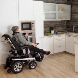Man using a bariatric power wheelchair to maneuver around his kitchen. 