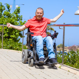 Man riding in wheelchair on sidewalk