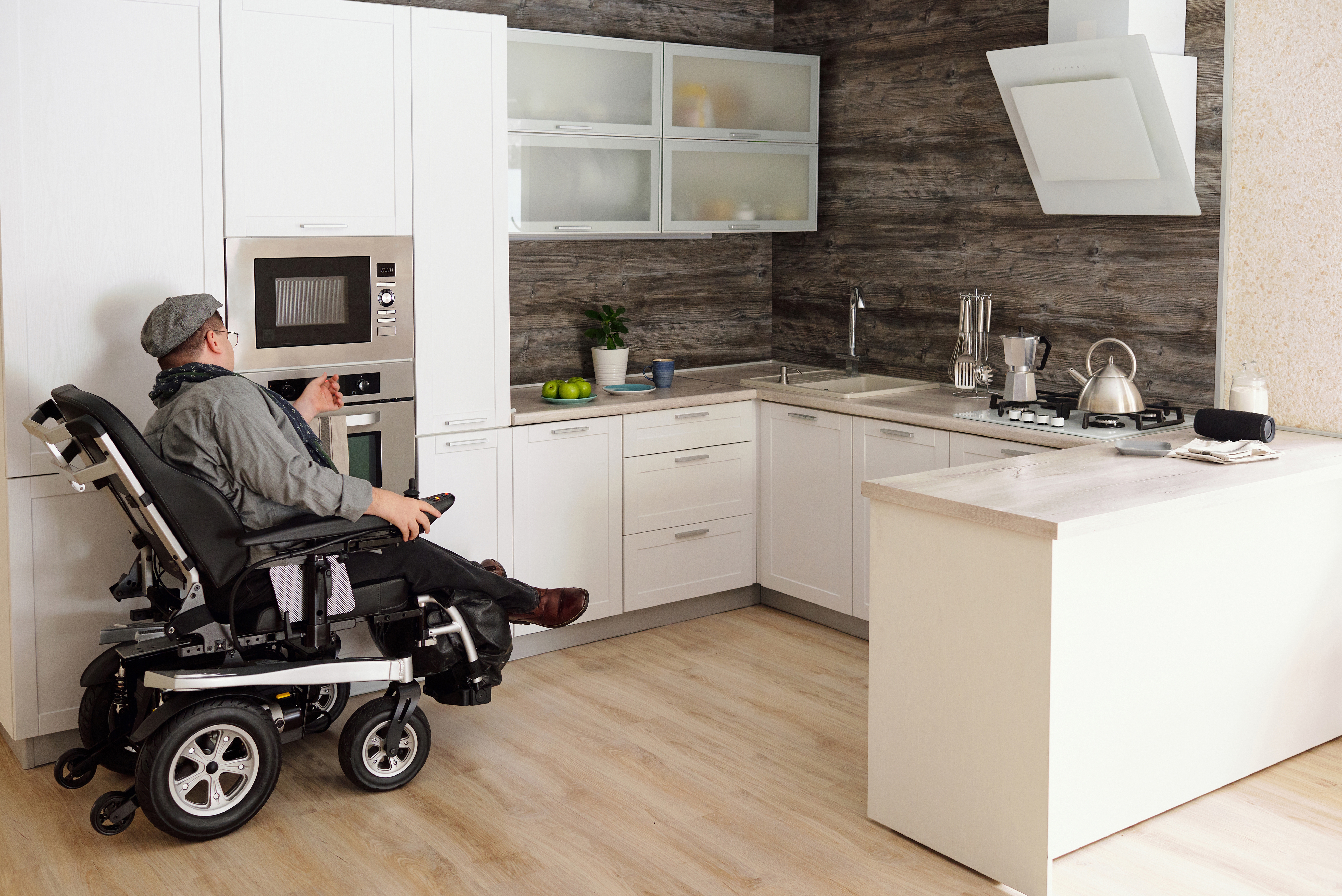 Man using a bariatric power wheelchair to maneuver around his kitchen. 