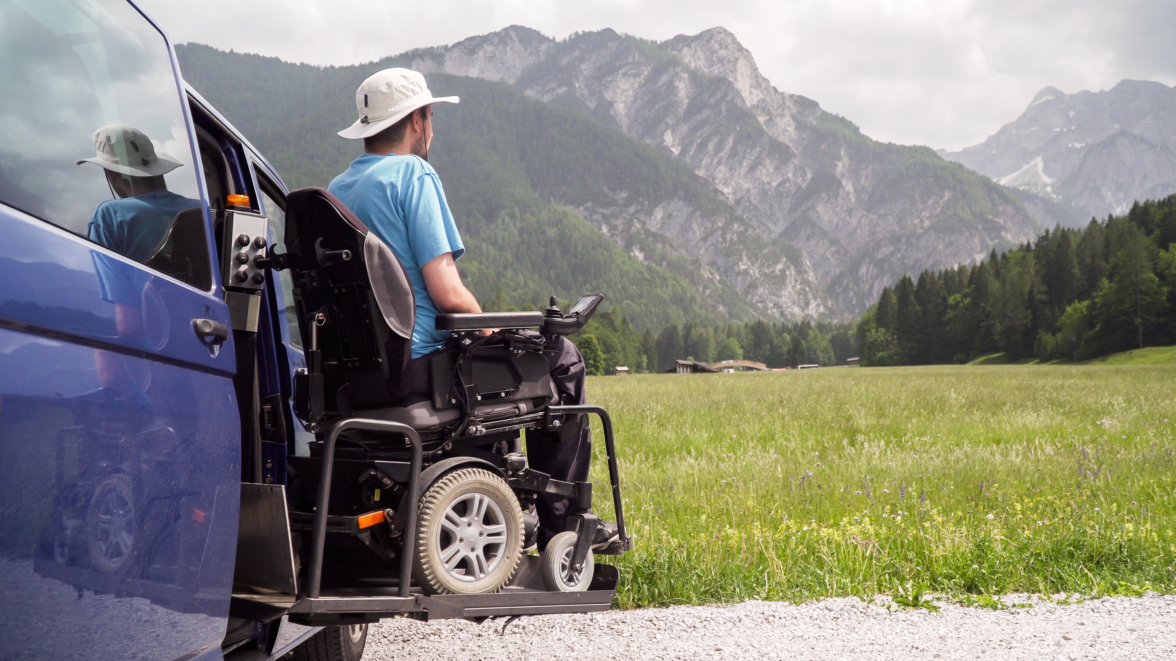 A man in an electric wheelchair being lowered down with a vehicle lift. 
