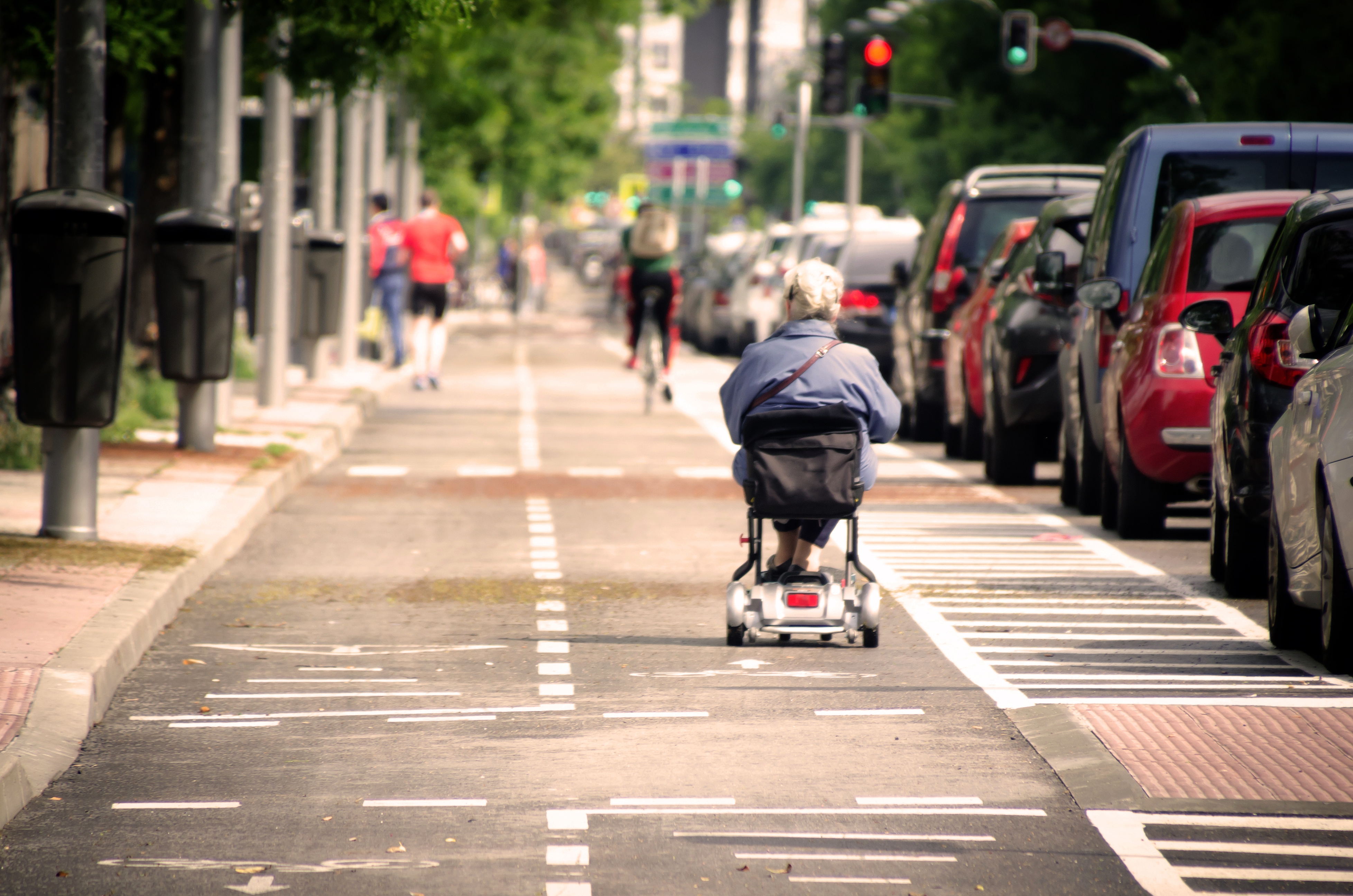 Older woman driving down the street in an electric wheelchair. 