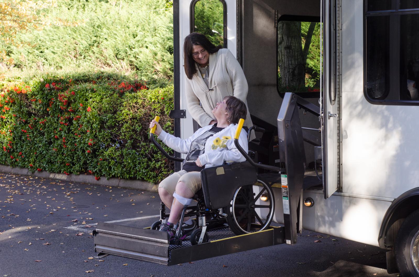 Woman disembarking a public bus in her wheelchair using the electric lift. 