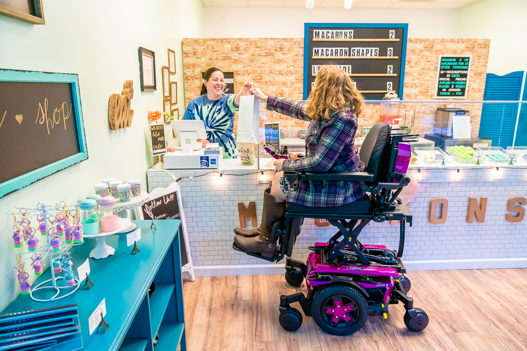 woman in power chair at register of sweets shop